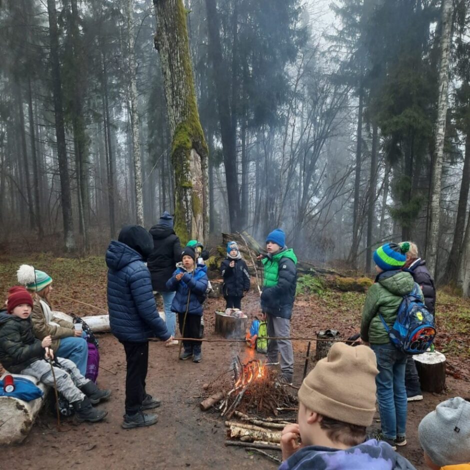 Skolēni sēd ap ugunskuru parkā