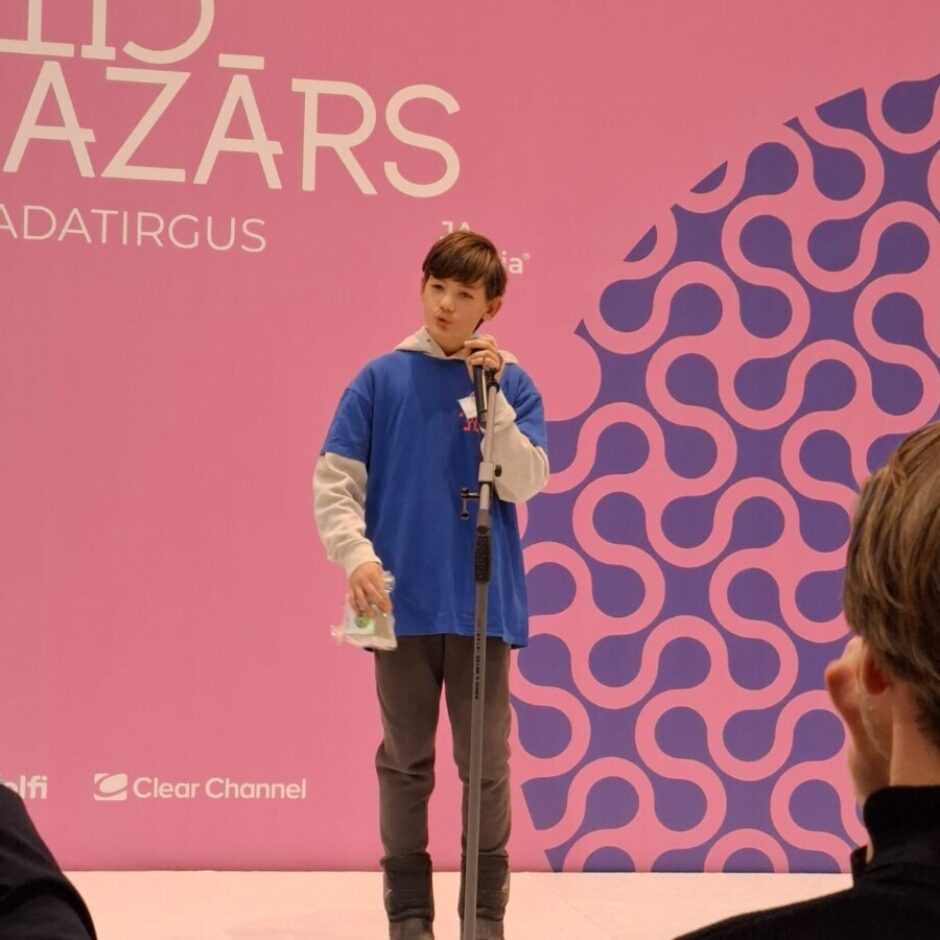 Skolēns uz skatuves prezentē savu projektu