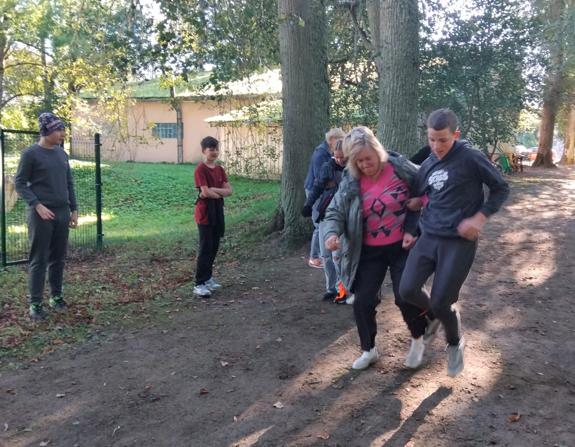Skolotāja un skolēni skrien ar kopā sasietām kājām