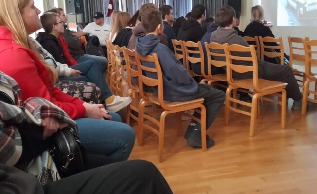 Skolēni sēž zālē un klausās lekciju