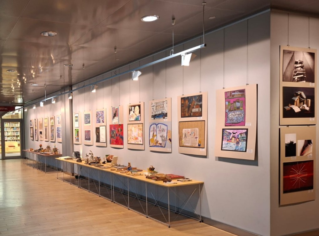 Skolēnu darbi izstādē pie sienas