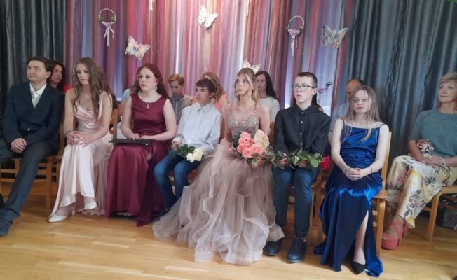 Skolēni sēž skolas zāles priekšā