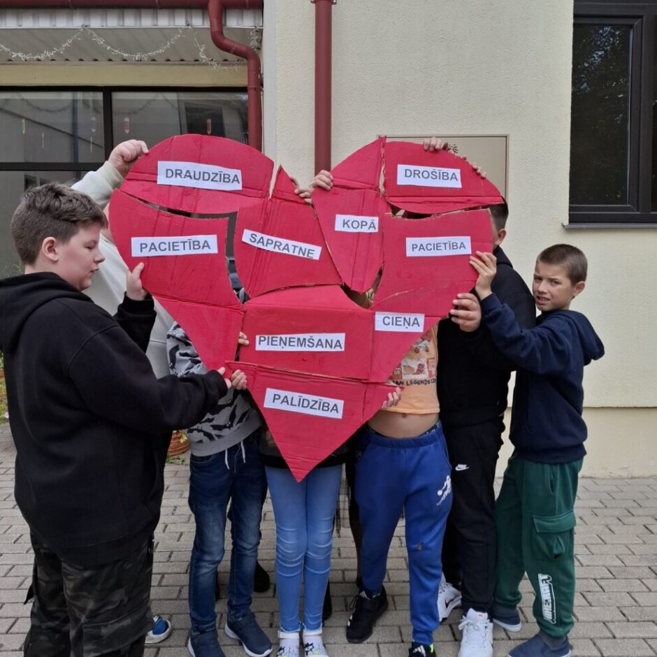 Skolēni ar savu darbu sirds formā