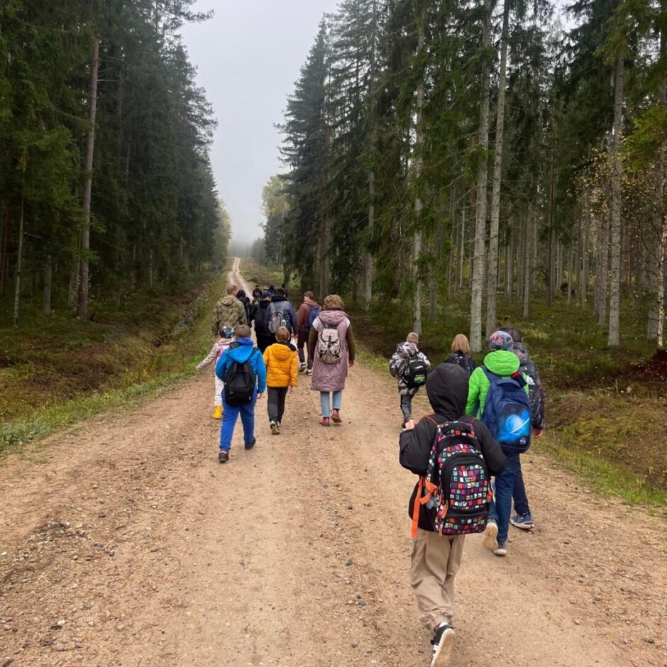 Skolēni iet pa meža taku